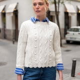 Natural cable-knit sweater with a traditional braided pattern and striped collar accents.