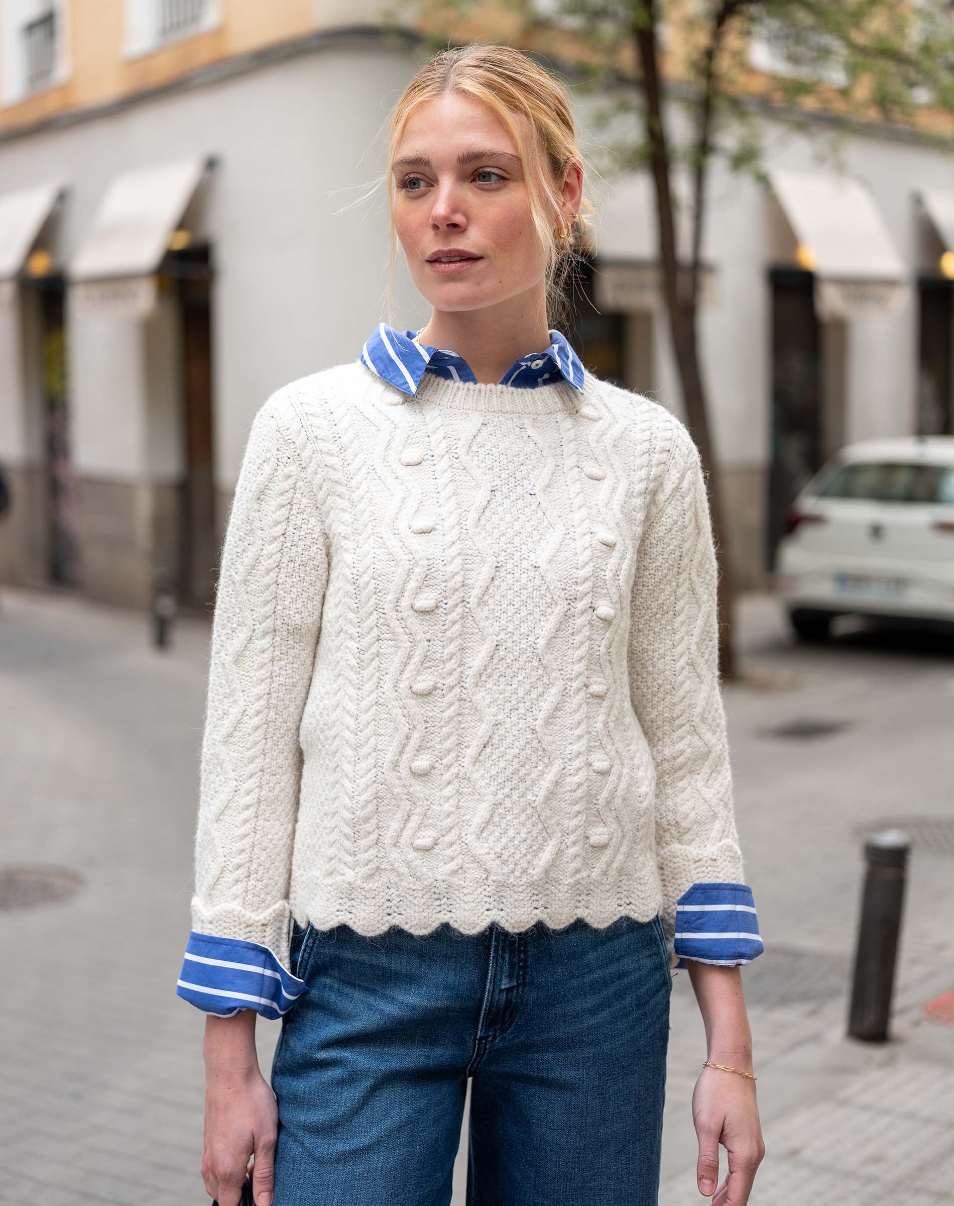 Natural cable-knit sweater with a traditional braided pattern and striped collar accents.