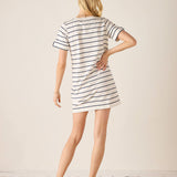 Woman wearing a striped dress with red shoes on a plain background