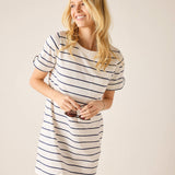 Woman wearing a white and navy striped dress against a plain background