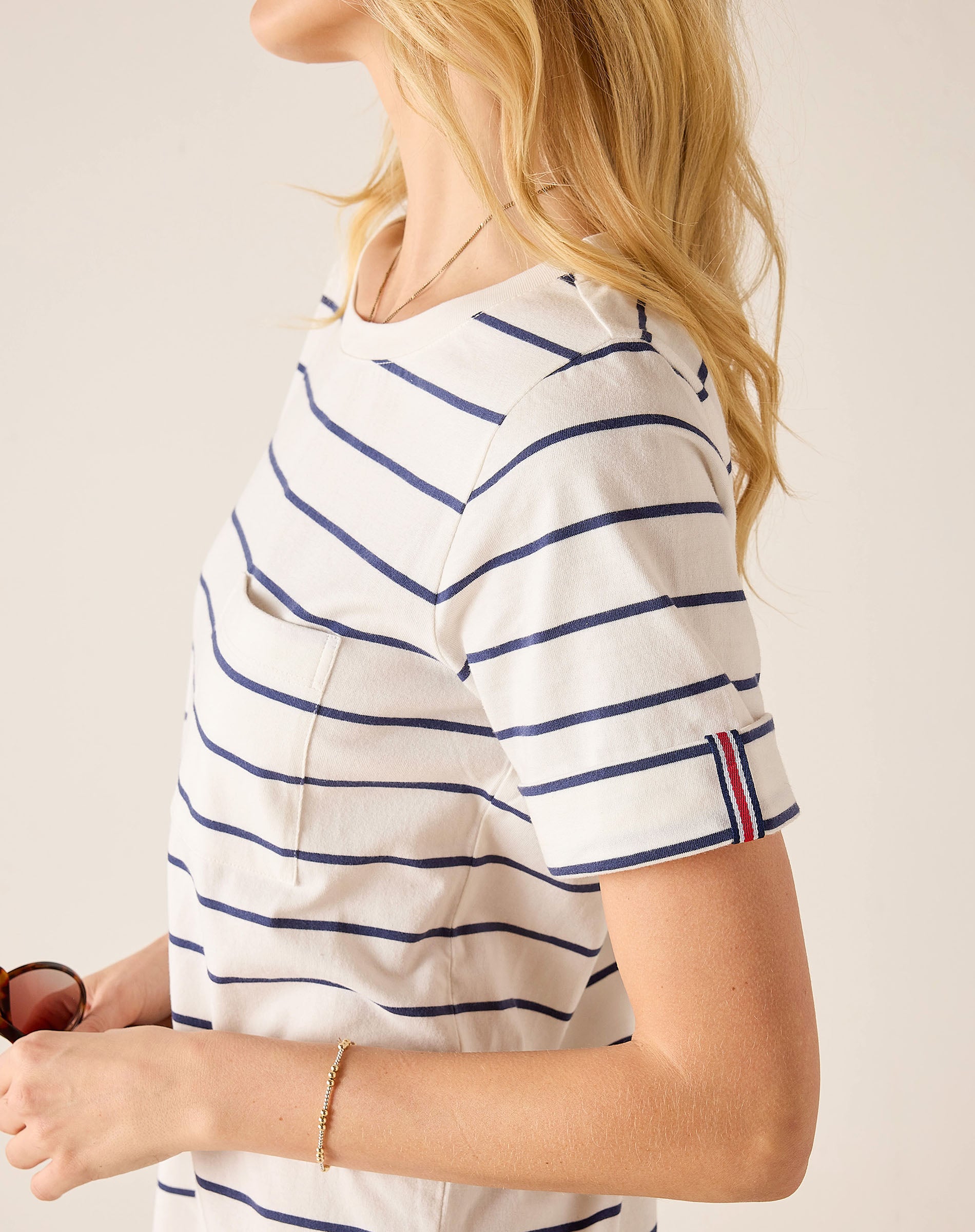 Person wearing a white and blue striped shirt with a red and blue trim on a plain background