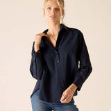 Woman wearing a navy blue shirt and blue jeans against a beige background