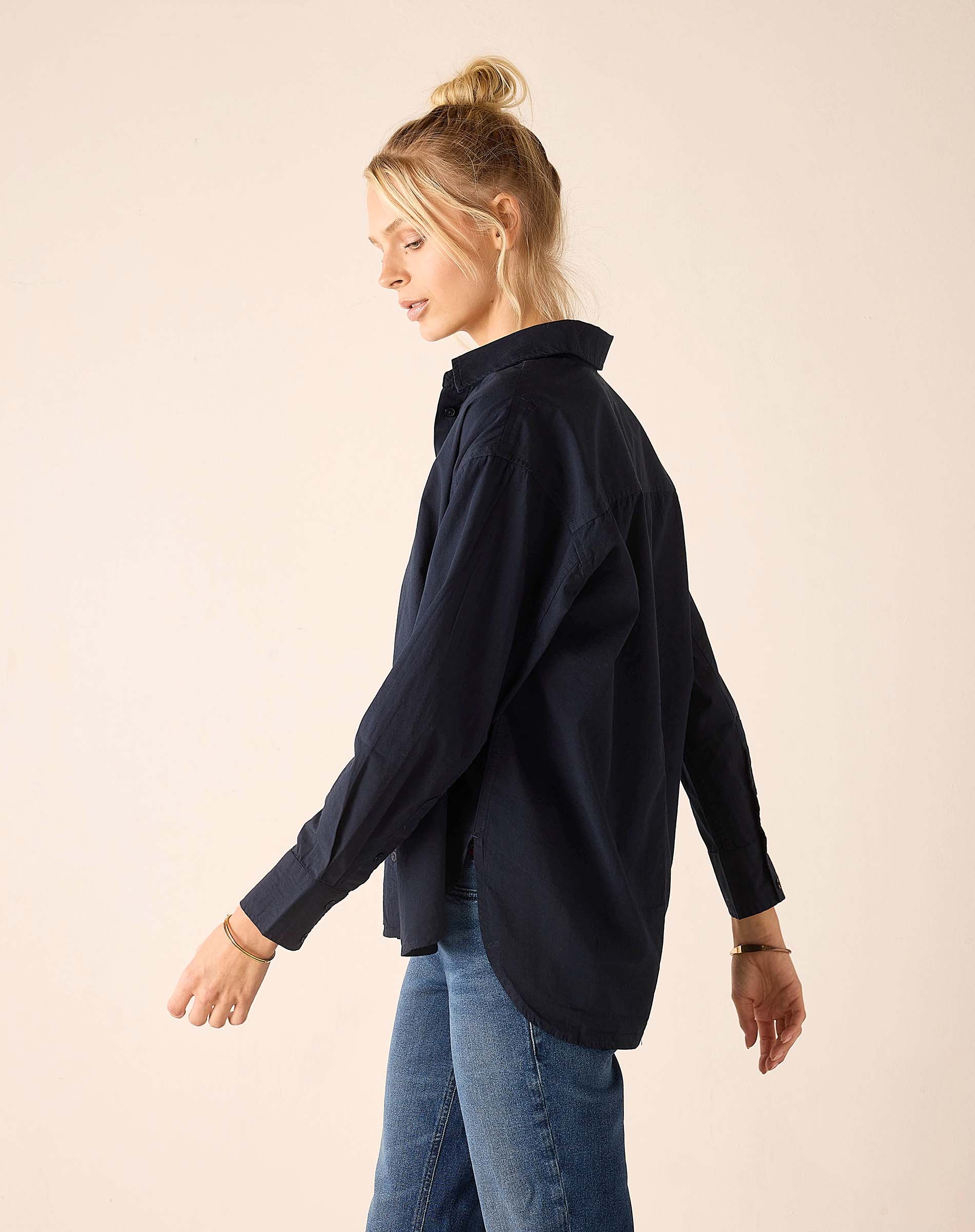 Woman wearing a navy shirt and blue jeans on a beige background