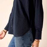 Person wearing a navy shirt and blue jeans on a beige background