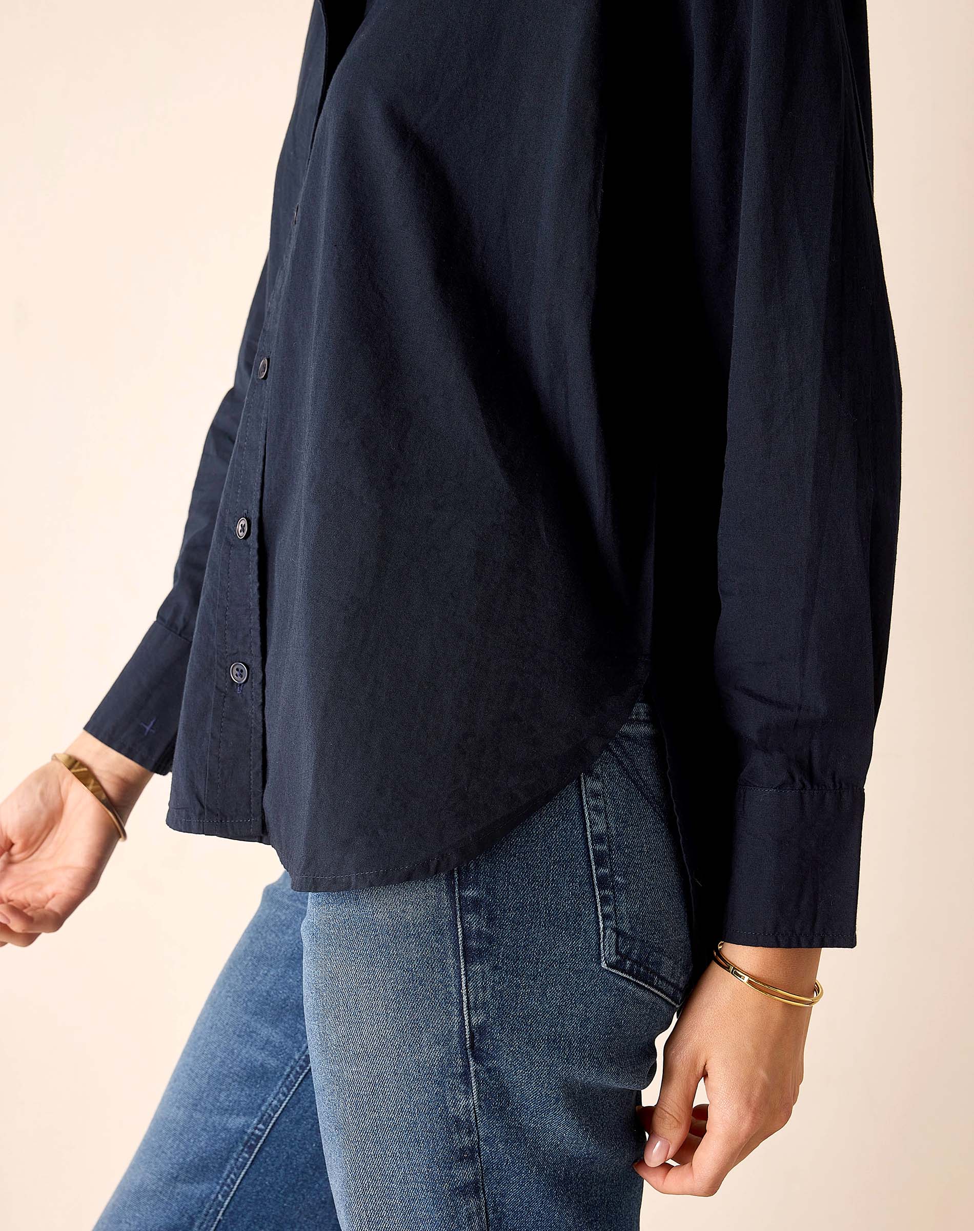 Person wearing a navy shirt and blue jeans on a beige background