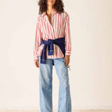 Woman wearing a striped shirt with a belt and jeans on a plain background