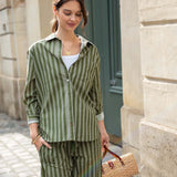 Woman in green striped outfit holding a straw bag against a building background