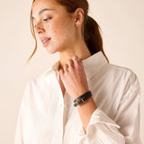 Woman wearing a white shirt and black bracelet on a beige background