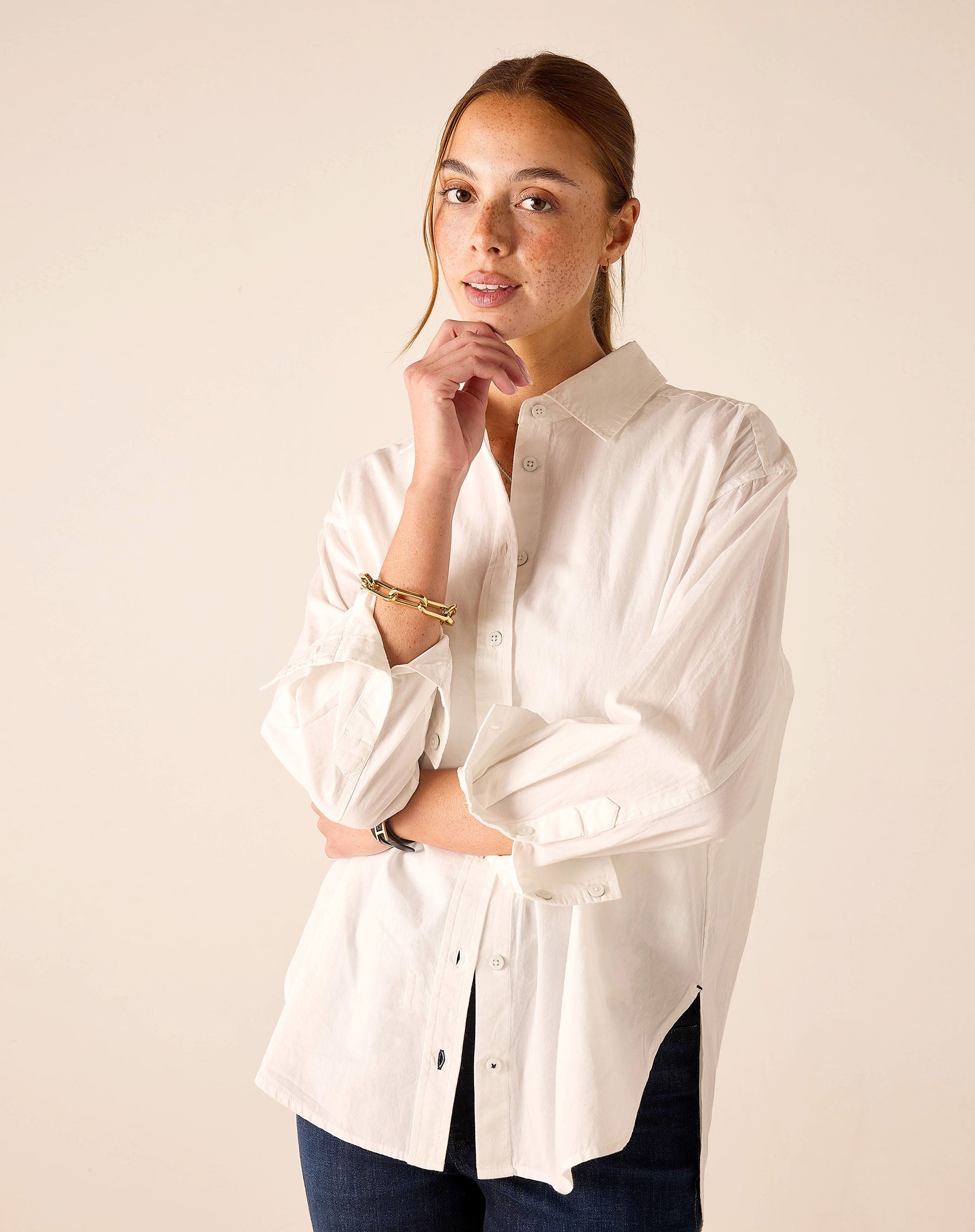 Woman wearing a white button-up shirt against a beige background