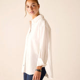 Woman wearing a white shirt and blue pants against a plain background