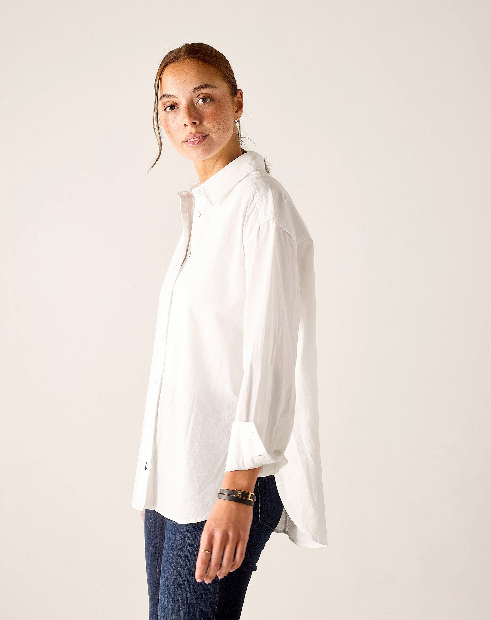 White oversized button-up linen shirt with wide sleeves and a curved hem.