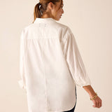 Woman wearing a white shirt with long sleeves on a beige background