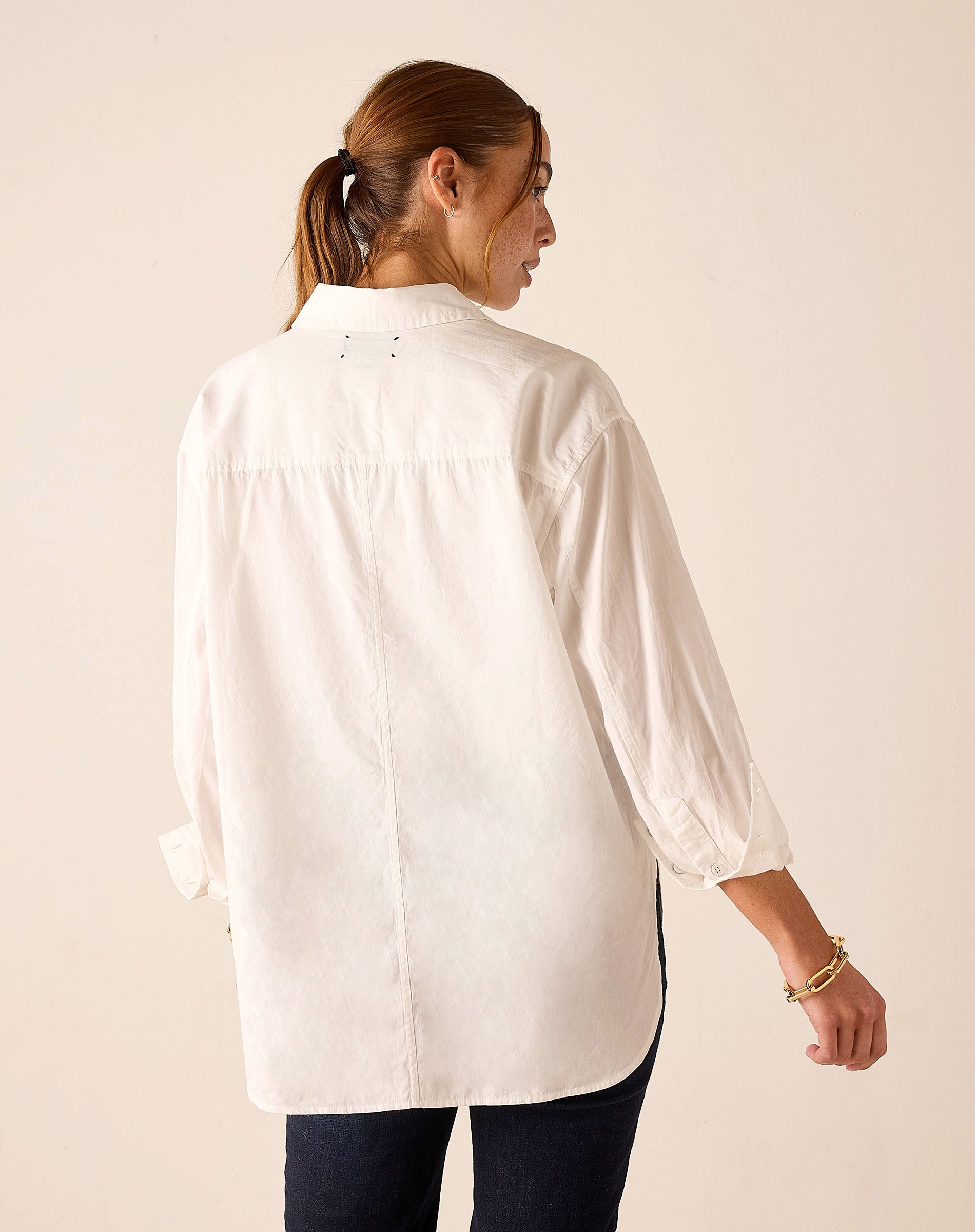 Woman wearing a white shirt with long sleeves on a beige background