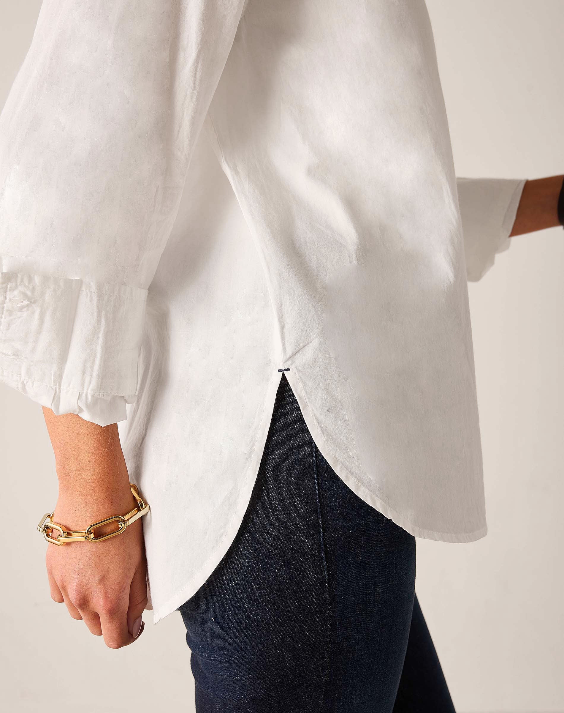 White button-up linen shirt with flared sleeves and ruffled trim.