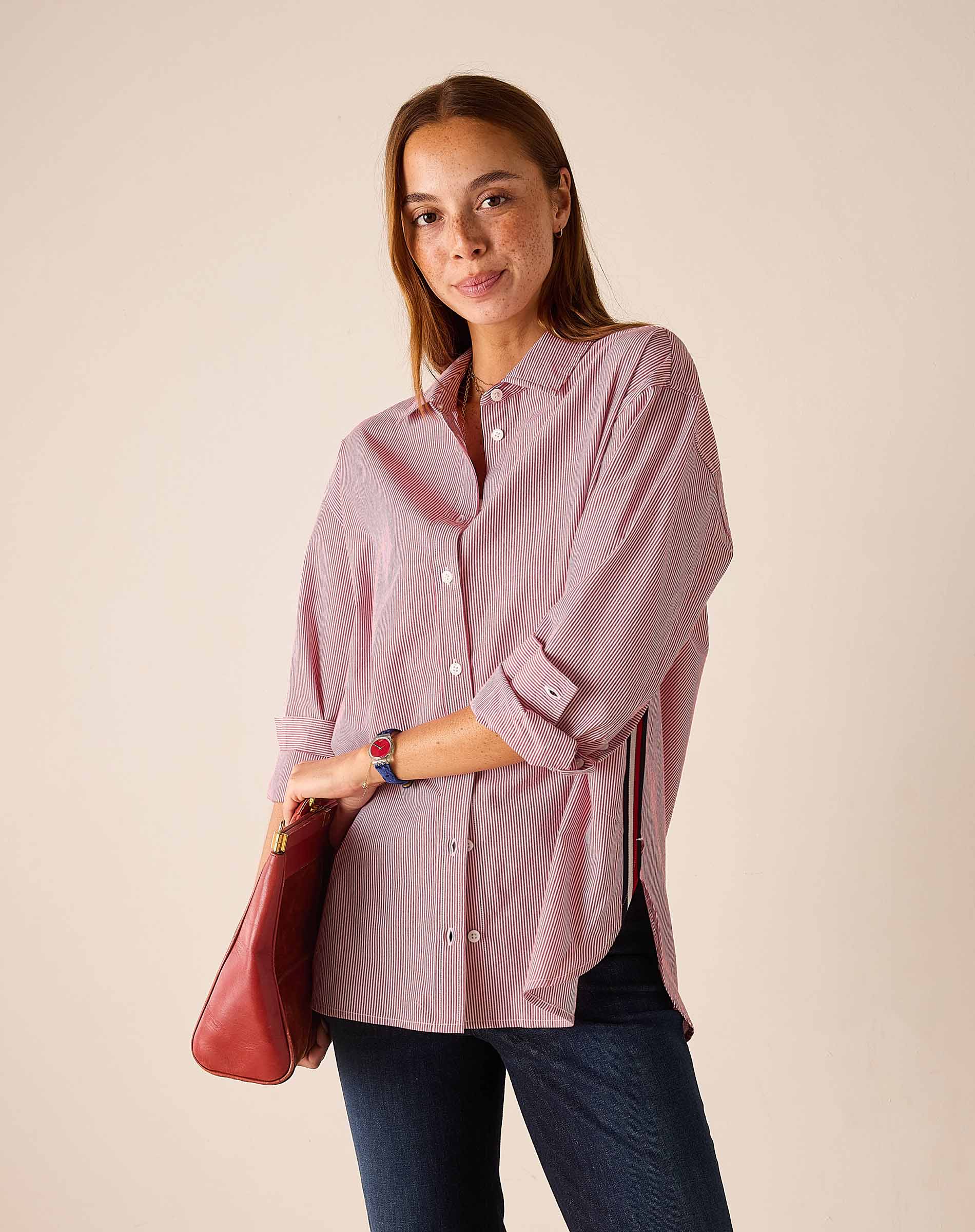 Women's travel-friendly cardinal pinstripe button-down shirt with long sleeves and a leather bag.