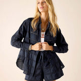 Woman wearing a navy blue jacket and shorts set on a beige background