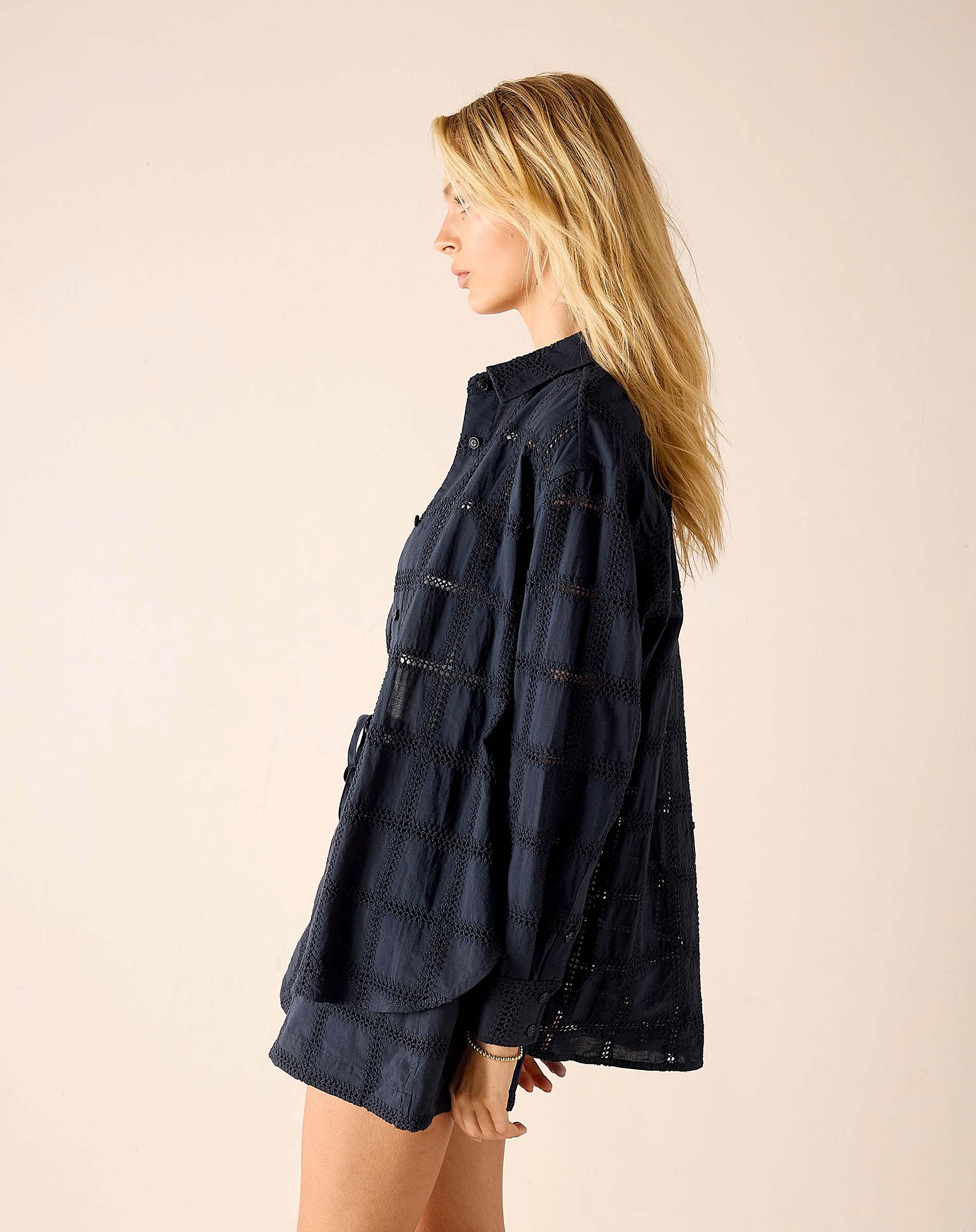 Woman wearing a dark denim shirt against a beige background