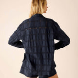 Woman wearing a dark denim jacket and shorts on a beige background
