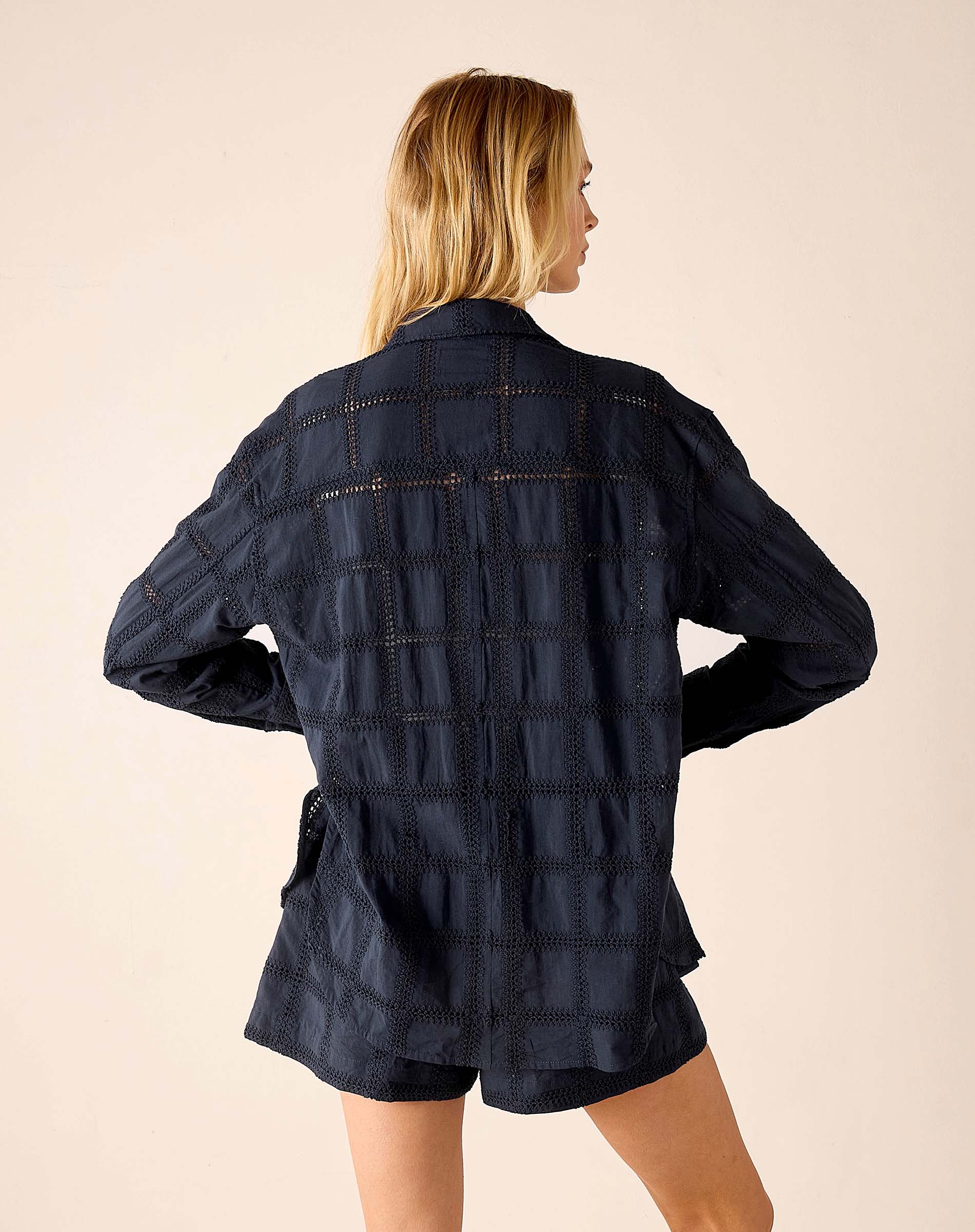Woman wearing a dark denim jacket and shorts on a beige background