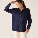 Woman wearing a navy blue shirt with white pants against a plain background