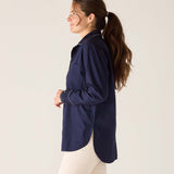 Woman wearing a navy blue shirt and white pants against a plain background