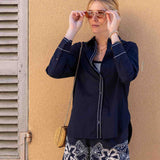 Woman wearing a navy jacket and floral shorts against a beige wall.