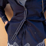 Navy blue jacket with white floral embroidery on a wooden surface