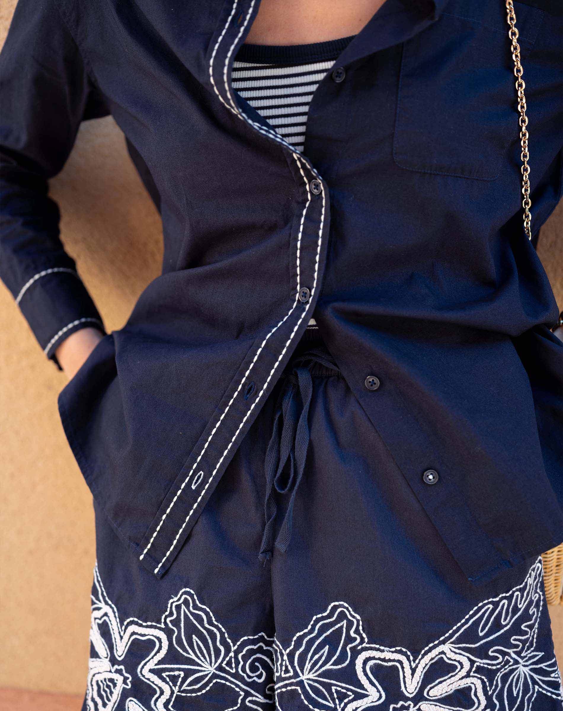 Navy blue jacket with white floral embroidery on a wooden surface