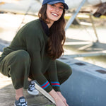 Woman tying a rope on a dock with a sailboat in the background