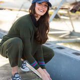Woman tying a rope on a dock with a sailboat in the background