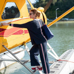 Woman boarding a yellow seaplane with a blue bag