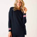 Woman wearing a navy sweater with red and white stripes on a plain background