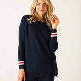 Woman wearing a navy sweater with red and white stripes on a plain background