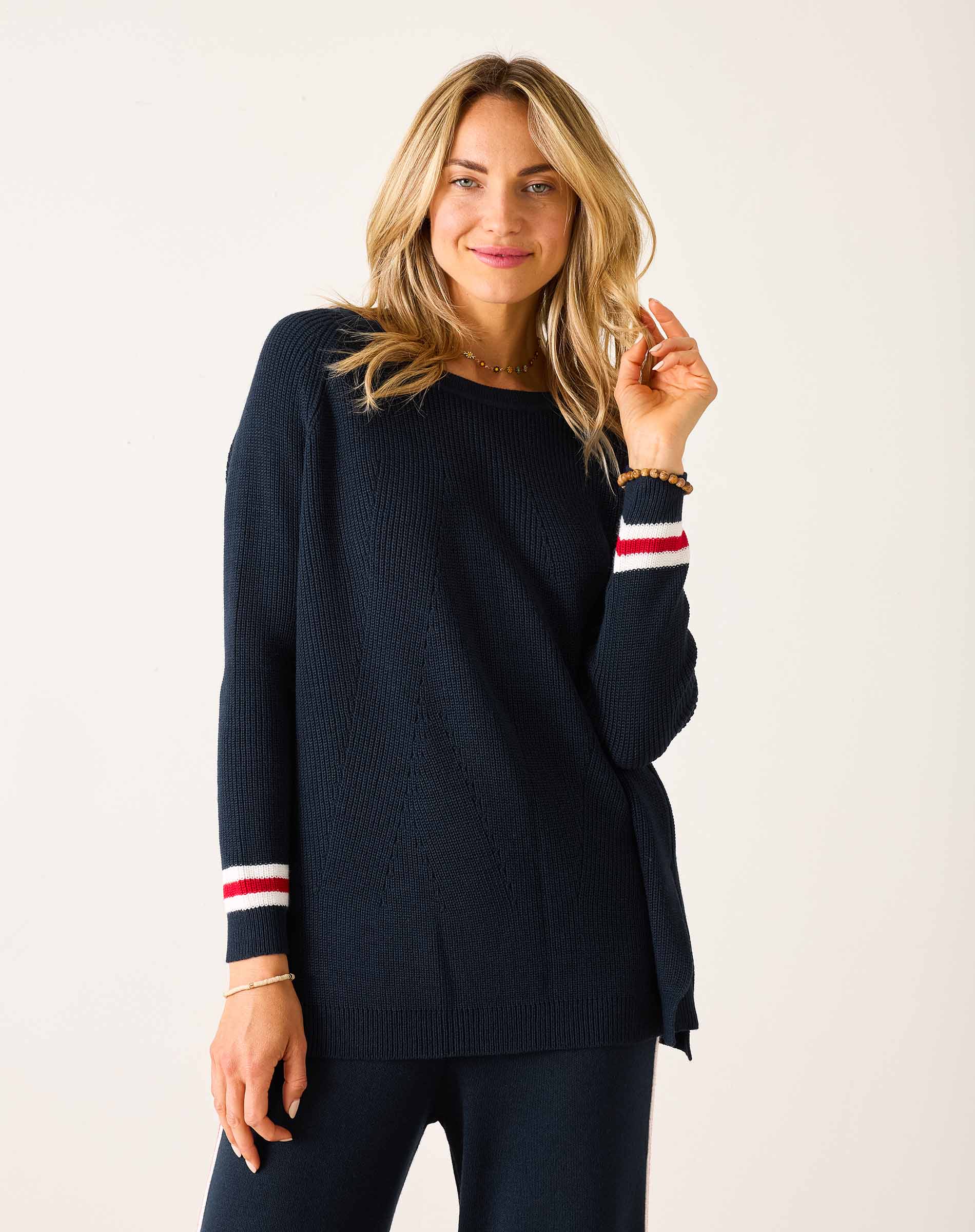 Woman wearing a navy sweater with red and white stripes on a plain background