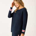 Woman wearing a navy sweater with white and red stripes on a white background