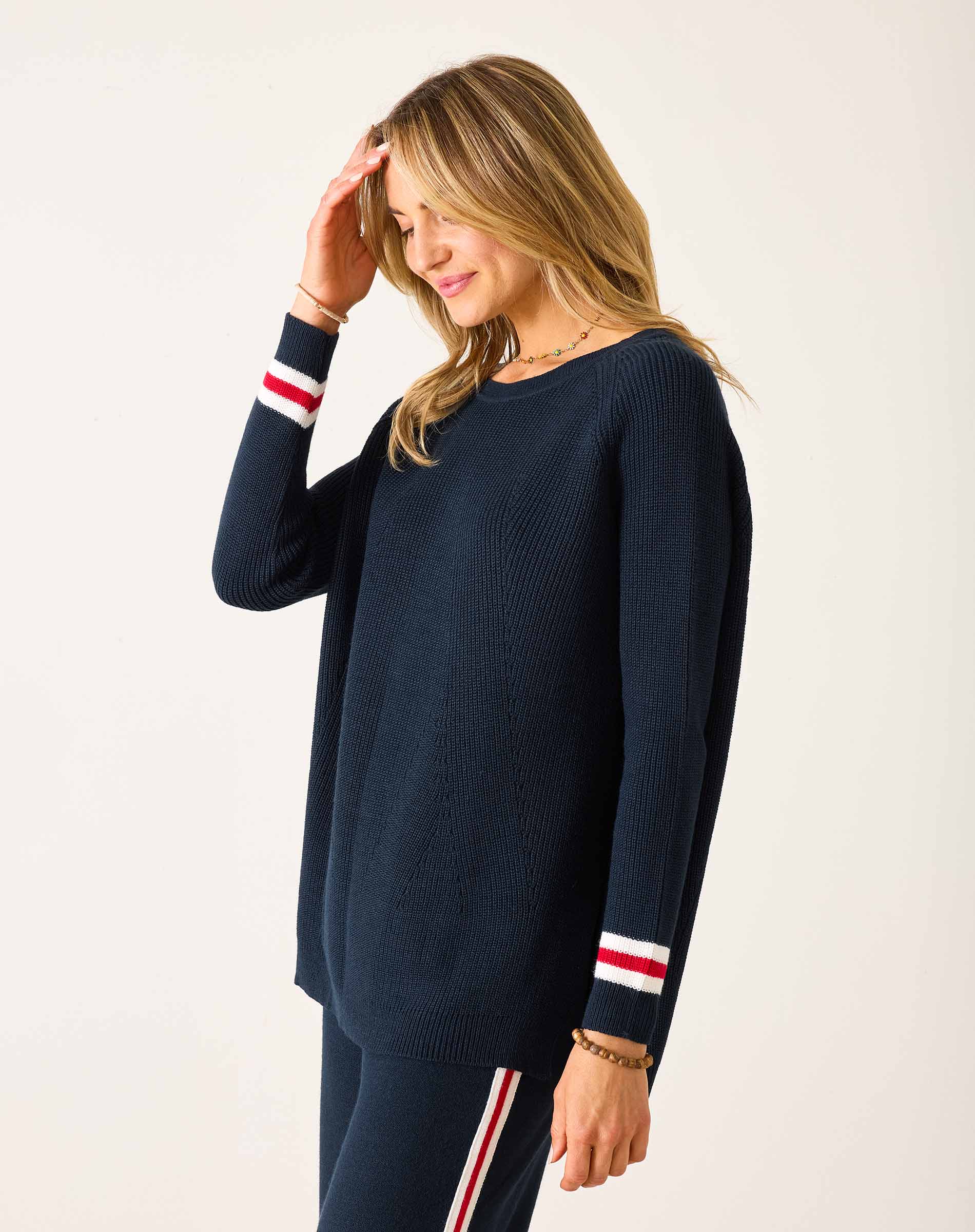 Woman wearing a navy sweater with white and red stripes on a white background