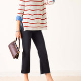 Person wearing a striped sweater, black pants, and brown sandals on a white background