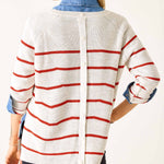 Person wearing a white cardigan with red stripes on a plain background