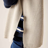 Desert palm beige knit vest with a textured cable stitch detail over a striped top.