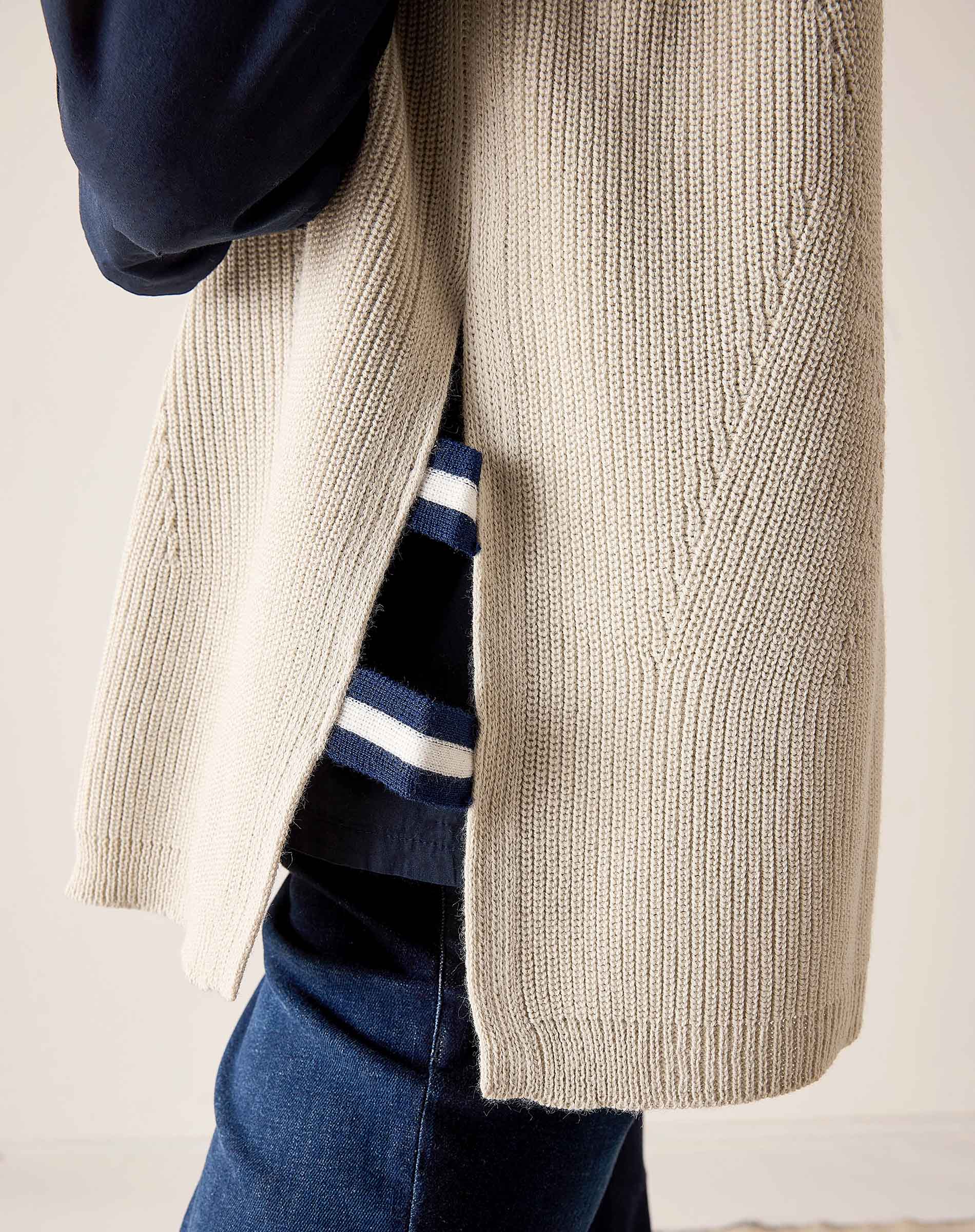Desert palm beige knit vest with a textured cable stitch detail over a striped top.