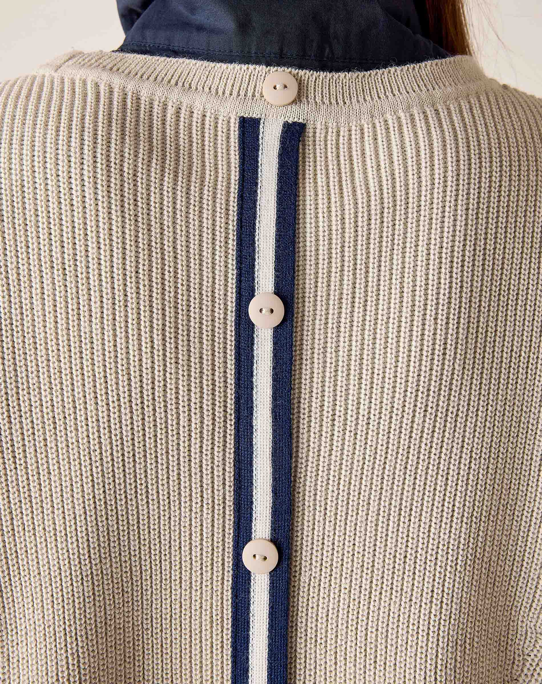 Detail of the desert palm color knit vest with vertical stripes and button closure.