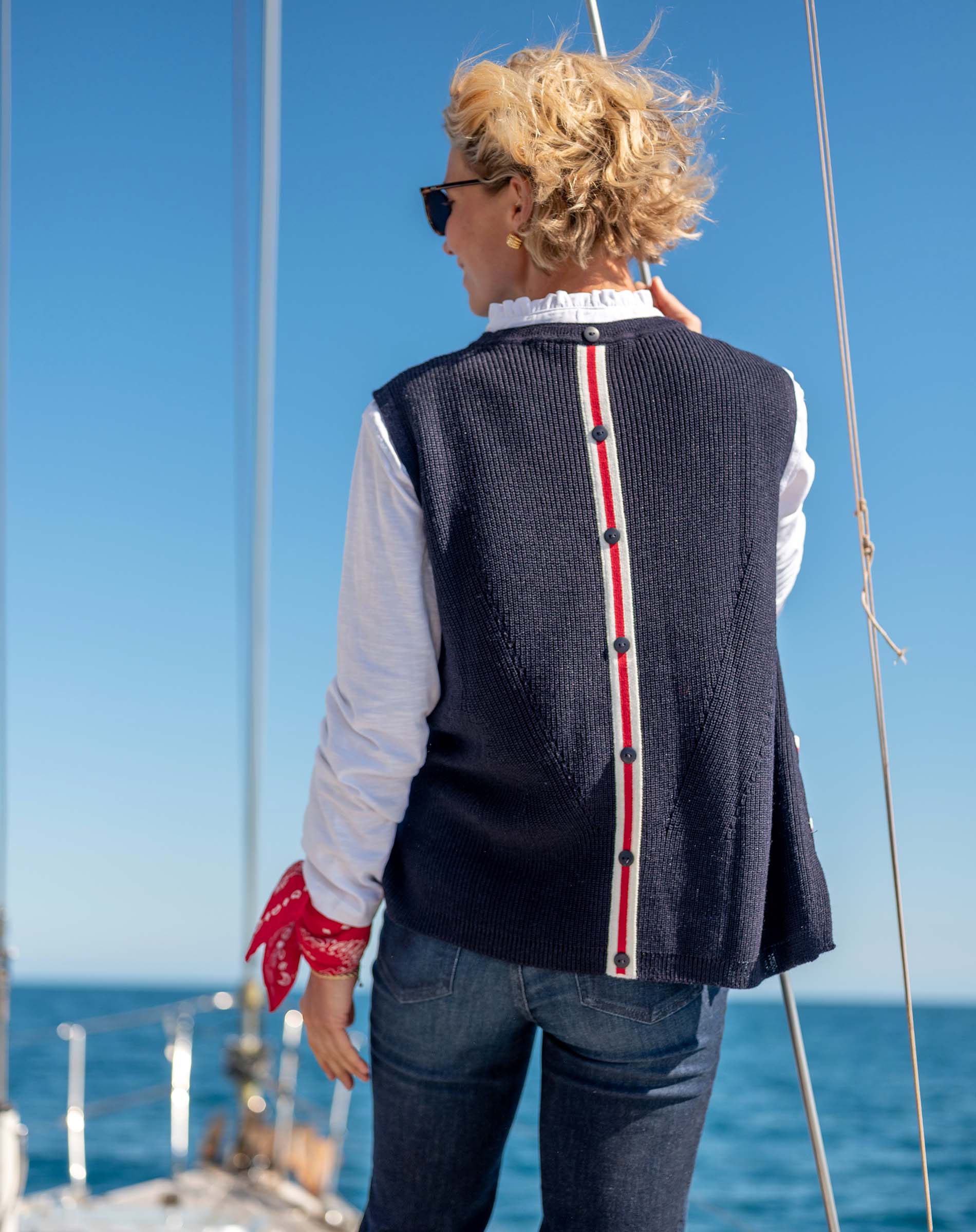 Back view of women's travel-friendly navy knit vest with buttoned red and white stripe detail.
