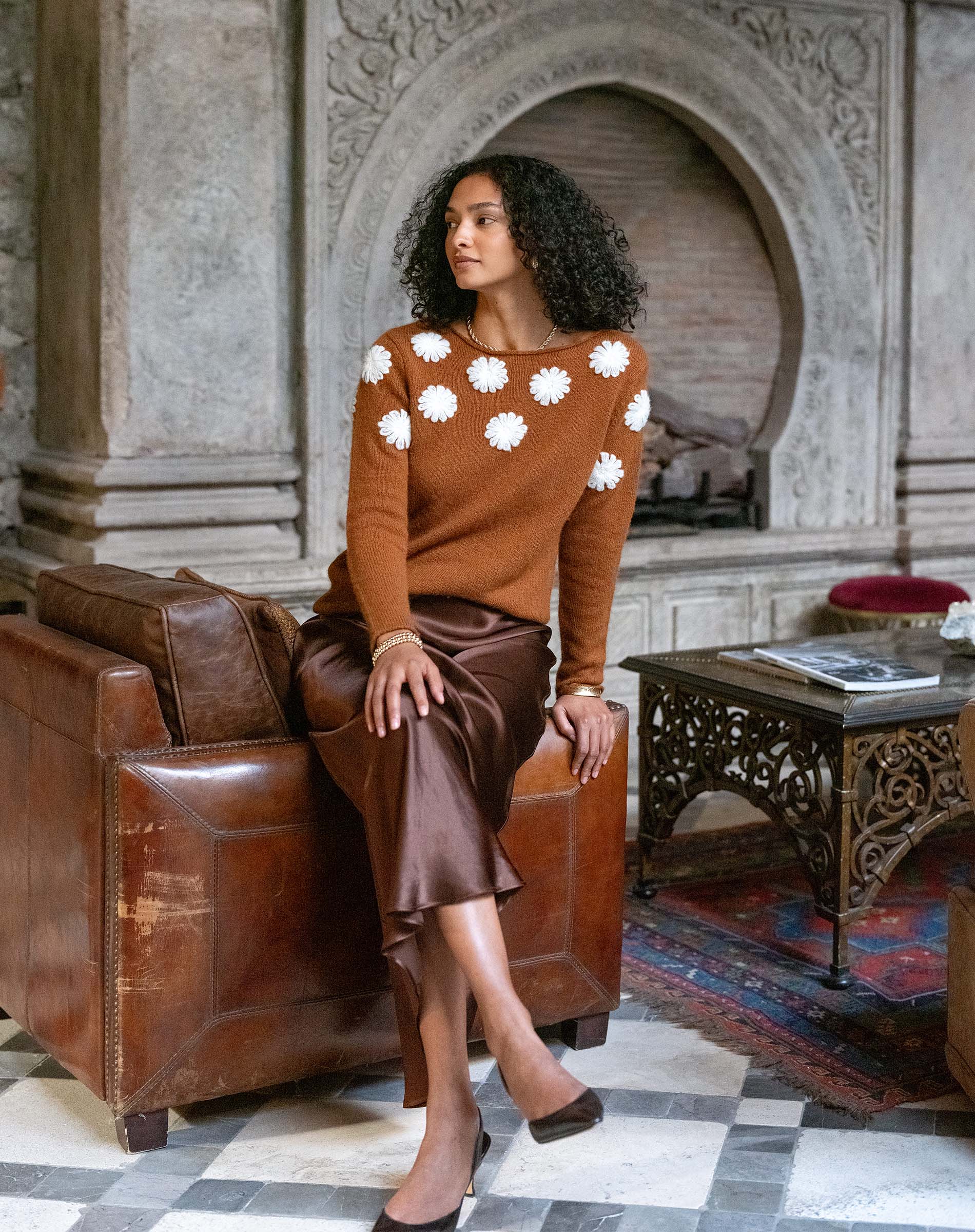 Women's travel-friendly cinder brown cashmere knit sweater featuring white camellia flower embroidery and a matching satin skirt.