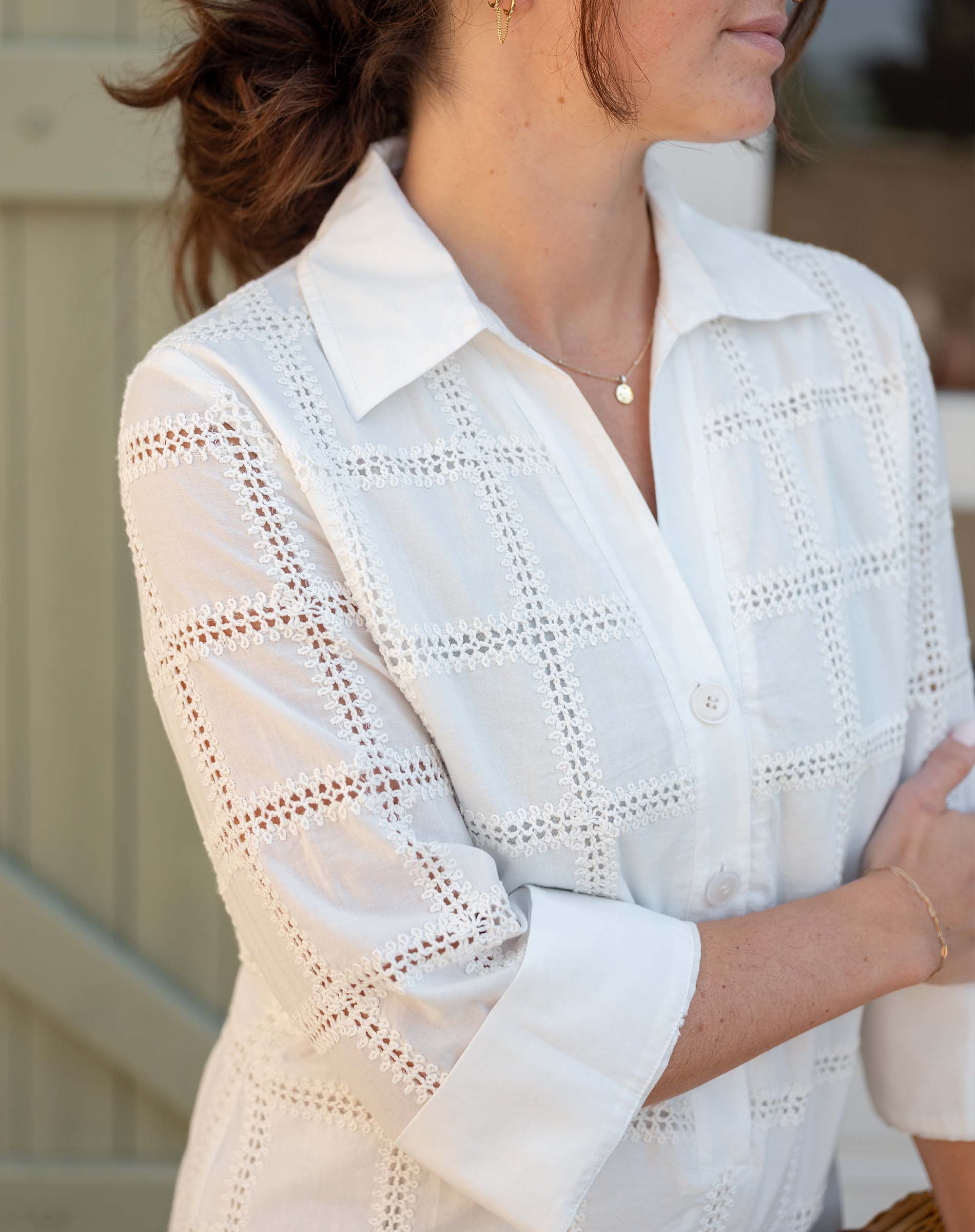White lace blouse worn by a person with a blurred background