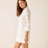 Woman wearing a white checkered dress against a beige background