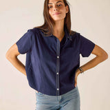 Woman wearing a navy blue shirt and light blue jeans against a plain background