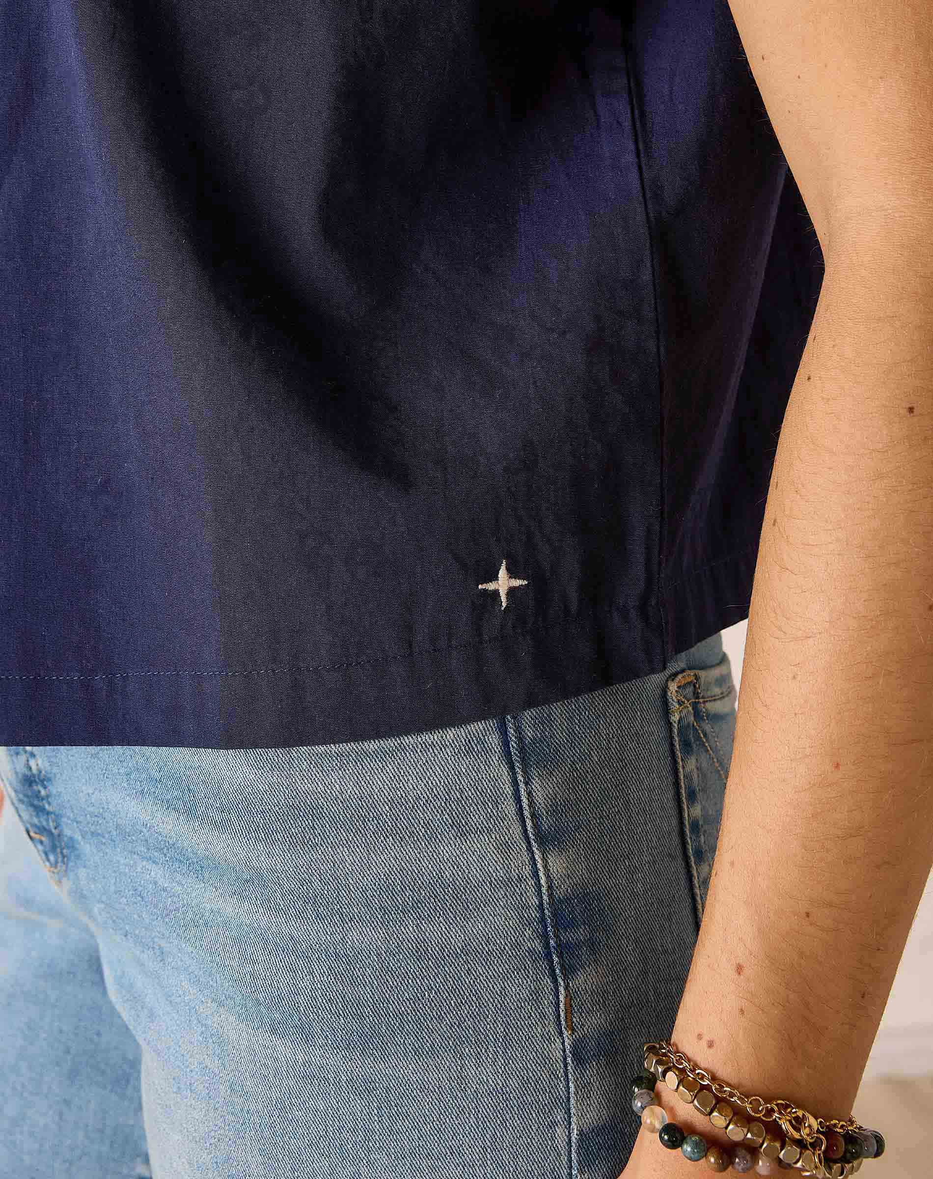 Navy shirt, blue jeans, and bracelets on a neutral background