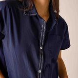 Navy blue shirt with white stitching worn by a person on a beige background