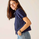 Woman wearing a navy blue shirt and light blue jeans against a plain background