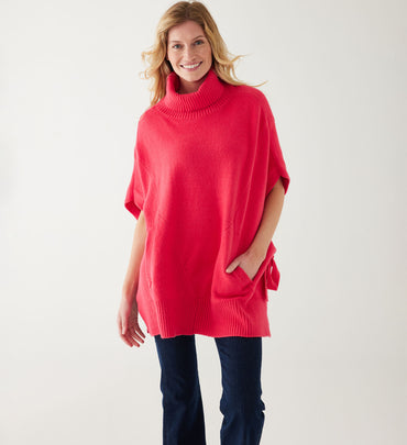 woman wearing mersea cape poncho sweater in hibiscus red